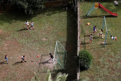 Vue aérienne de quelques garçons jouant au football tandis que des filles jouent sur les balançoires, à Rome (Italie). 
