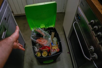 Un homme jette des filets expirés vers la poubelle de sa cuisine.