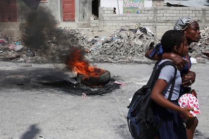 Un groupe de personnes passe par une barre de flammes installée pour protester contre l'insécurité, dans le quartier Tabarre de Puerto Príncipe, Haïti, le 24 février 2025. 