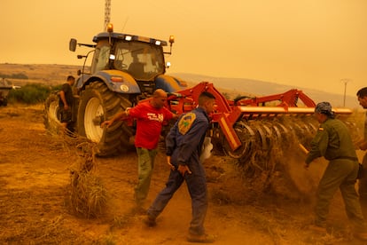Un groupe de bénévoles et de voisins préparent un tracteur à faire des pare-feu.
